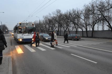 Люди переходят дорогу по пешеходному переходу.  Троллейбус уступает дорогу пешеходам. 01 декабря 2011 года.