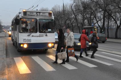 Люди переходят дорогу по пешеходному переходу. Троллейбус уступает дорогу пешеходам. 01 декабря 2011 года.