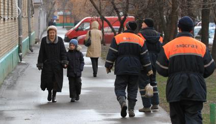 Бабушка с внуком идет по улице, мимо проходят рабочие из МОСГАЗа. 5 декабря 2011 года.