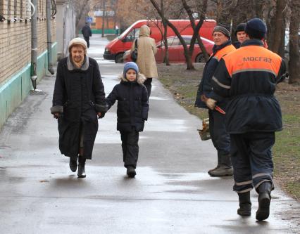 Бабушка с внуком идет по улице, мимо проходят рабочие из МОСГАЗа. 5 декабря 2011 года.