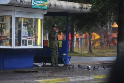 Военнослужащий грызет семечки на автобусной остановке, Плесецк, 03 ноября 2011 года