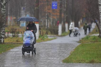 Женщина с коляской идет под зонтом в военном городке, Плесецк, 3 ноября 2011 года