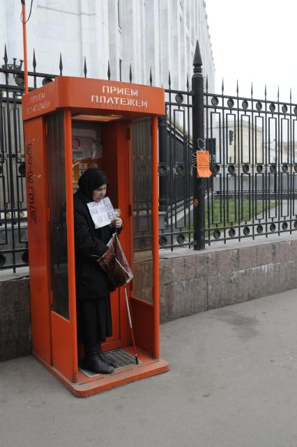 Жанровая фотография. Женщина просит милостыню в кабинке приема платежей на улице. 04 декабря  2009 года.