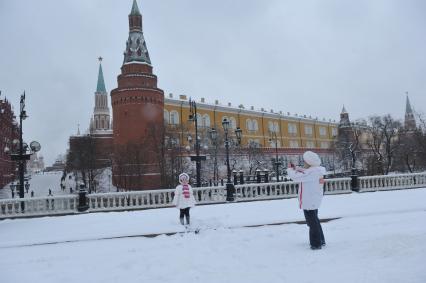 Жанровая фотография. Зимняя прогулка с мамой. На снимке: женщина фотографирует девочку на фоне Кремлевской башни.  Москва. 21 декабря  2011 года.