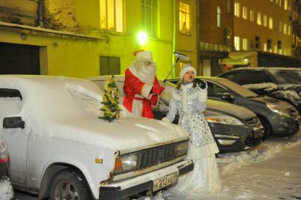 Жанровая фотография. Снегурочка пьет шампанское у автомобиля. Дед Мороз держит в руках щетку для чистки автомашины. 21 декабря  2011 года.