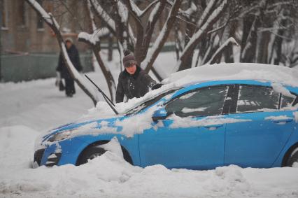 Зима в городе. Снегопад. На снимке: водитель чистит автомобиль от снега. 22 екабря  2011 года.