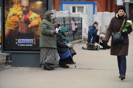 Бабки просят милостыню на автобусной остановке с надписью \"Когда голоден\", Москва,  30 ноября  2011  года