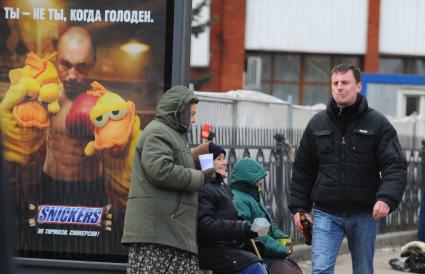 Бабки просят милостыню на автобусной остановке с надписью \"Когда голоден\", Москва,  30 ноября  2011  года