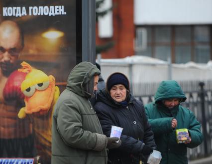 Бабки просят милостыню на автобусной остановке с надписью \"Когда голоден\", Москва,  30 ноября  2011  года