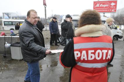 Женщина на улице распространяет бесплатную газету по трудоустройству \"Работай рядом с домом\". Москва. 10 февраля 2009 года.