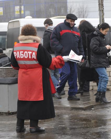 Женщина на улице распространяет бесплатную газету по трудоустройству \"Работай рядом с домом\". Москва. 10 февраля 2009 года.