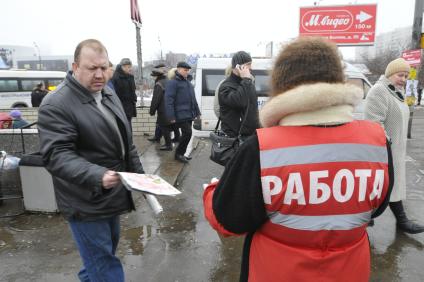 Женщина на улице распространяет бесплатную газету по трудоустройству \"Работай рядом с домом\". Москва. 10 февраля 2009 года.