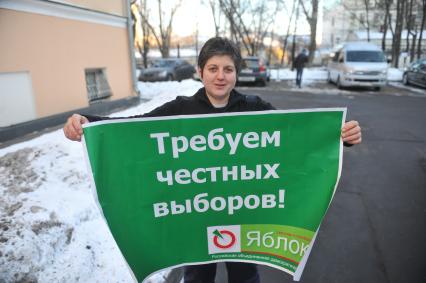Женщина держит плакат пратии ЯБЛОКО с надписью ТРЕБУЕМ ЧЕСТНЫХ ВЫБОРОВ!. 27 января 2012 года.