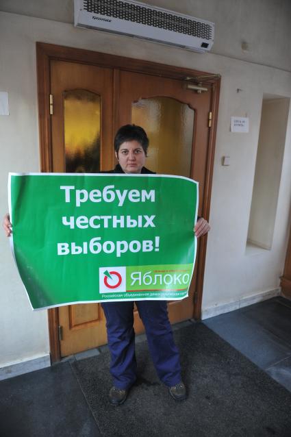 Женщина держит плакат пратии ЯБЛОКО с надписью ТРЕБУЕМ ЧЕСТНЫХ ВЫБОРОВ!. 27 января 2012 года.