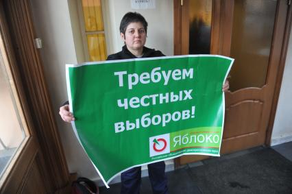 Женщина держит плакат пратии ЯБЛОКО с надписью ТРЕБУЕМ ЧЕСТНЫХ ВЫБОРОВ!. 27 января 2012 года.