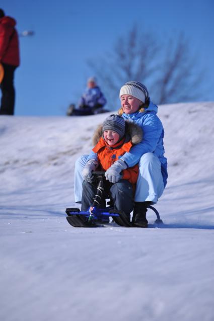 Зима. Зимние каникулы. Женщина с ребенком катятся с горки на снегокате.  29 января 2012