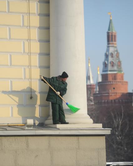 Мужчина метлой чистит снег на здании Манежа со стороны Сапожниковской площади, Москва, 3 февраля 2012 года