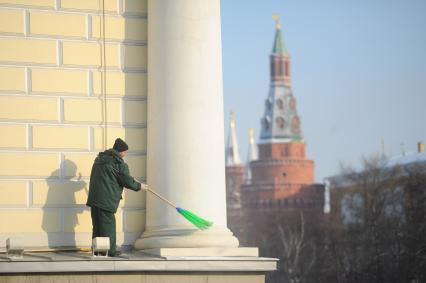 Мужчина метлой чистит снег на здании Манежа со стороны Сапожниковской площади, Москва, 3 февраля 2012 года