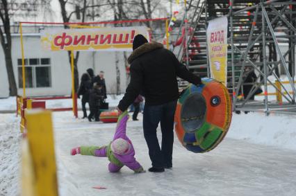 Зимняя прогулка с отцом.  На снимке: мужчина и ребенок на ледяной горке.