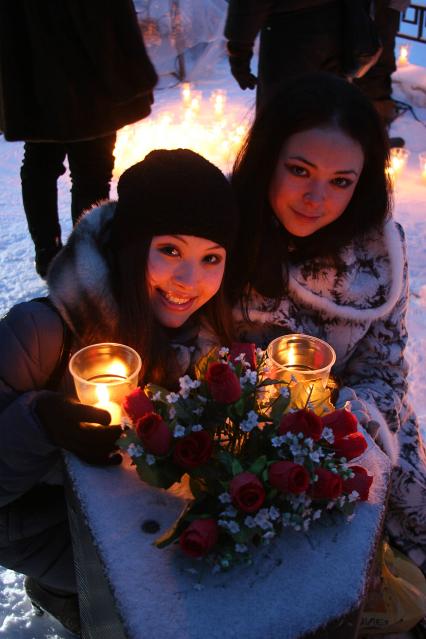 Девушки сидят около композиции со свечами и букетом цветов.