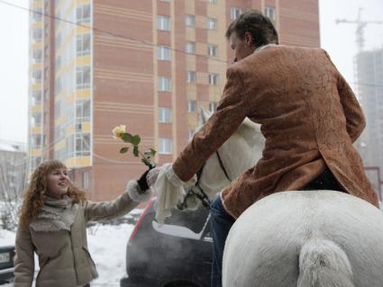 Мужчина на белом коне дарит девушке белую розу.