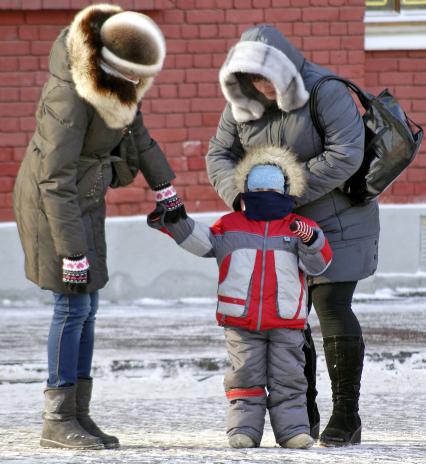 Родители укутывают ребенка. Мама повязывает шарф.