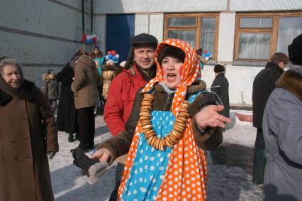 Женщина в праздничном наряде масленицы со связкой баранок на шее зазывает людей.