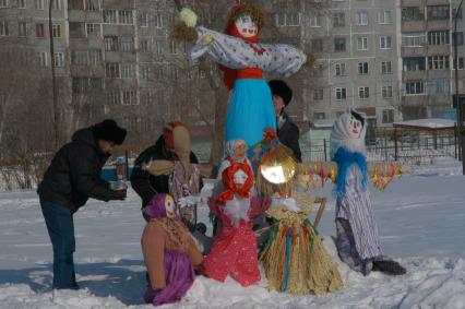 Люди устанавливают чучела маслениц.