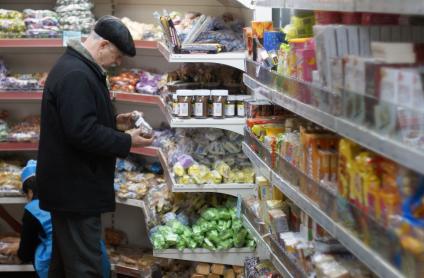 Мужчина у прилавка магазина осматривает продукты.