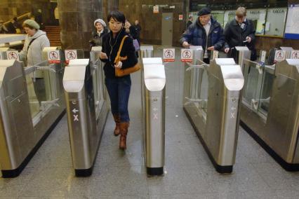 Люди проходят через турникеты в метро.