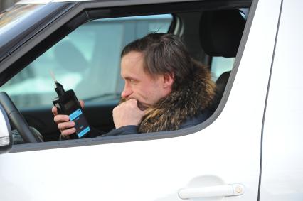 Водитель автомобиля проверяет себя на наличие алкоголя в крови.