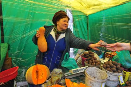 Ярмарка выходного дня. На снимке:  продавец овощной палатки.