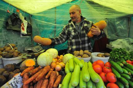 Ярмарка выходного дня. На снимке:  продавец овощной палатки.