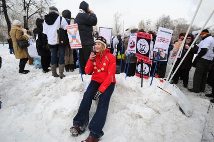 Девушка сидит в сугробе перед плакатами на митинге ЗА ЧЕСТНЫЕ ВЫБОРЫ, Москва, 4 февраля 2012 года