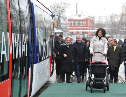 В Москве состоялась презентация трамвая нового поколения, совместная разработка франзузской фирмы `Alstom` и `Трансмашхолдинг`. На снимке: женщина с коляской перед посадкой в трамвай, на заднем плане мэр Москвы Сергей Собянин (третий слева).