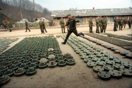 На плацу военного лагеря разложены мины.
Солдат перепрыгивает через ряды мин.