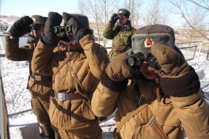 Трое солдат и офицер  смотрят в бинокли.