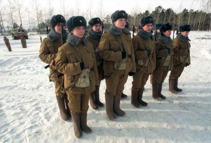 Девушки в военной форме с автоматами за спиной выстроились на площадке  для военный учений.