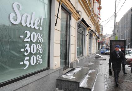 Надпись на стекле магазина: `Sale - 20%, - 30%, - 50%`.