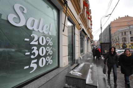 Надпись на стекле магазина: `Sale - 20%, - 30%, - 50%`.