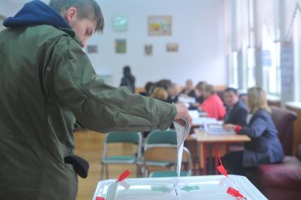 Житель Москвы опускает бюллетень во время голосования на выборах президента РФ на избирательном участке  78., Москва, 4 марта 2012 года