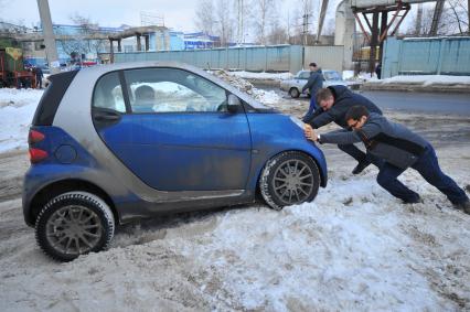 Поломка автомашины. На снимке: мужчины толкают руками автомобиль Smart (Смарт).