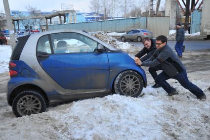 Поломка автомашины. На снимке: мужчины толкают руками автомобиль Smart (Смарт).