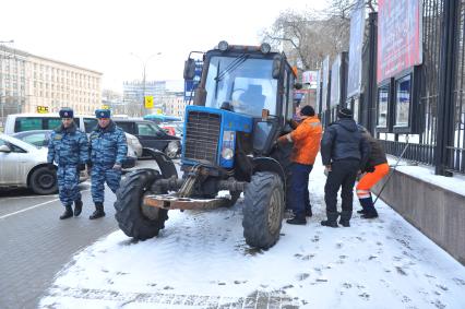 Поломка трактора для очистки тротуаров. На снимке: мужчины меняют колесо на тракторе.