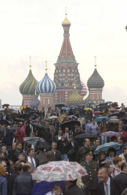 Толпа людей под зонтиками рядом с Храмом Василия Блаженного.