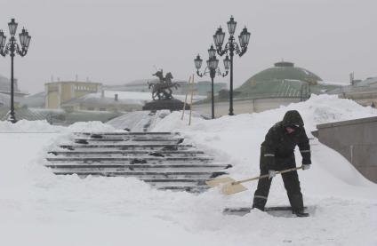 Дворник убирает снег на Манежной площади.