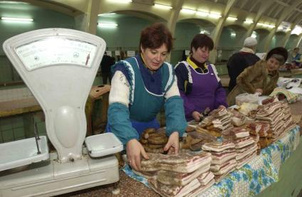 Женщины продают сало в мясном отделе на рынке.