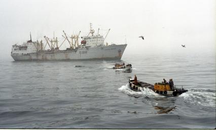 Рыбаки в море в туман на лодке на фоне парохода.