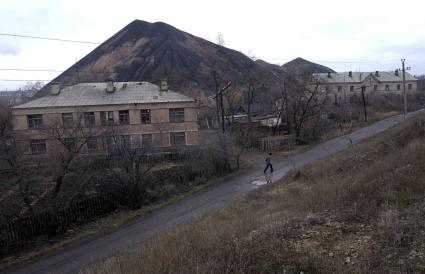 Дорога в провинциальном городе, проходящая мимо домов и горы.