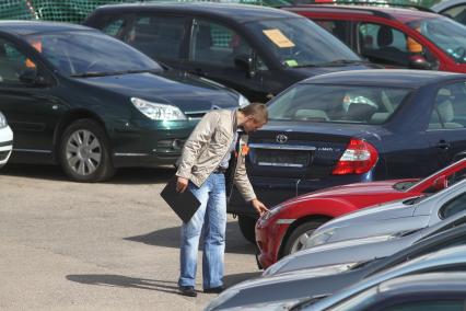 Мужчина выбирает автомобиль на рынке.